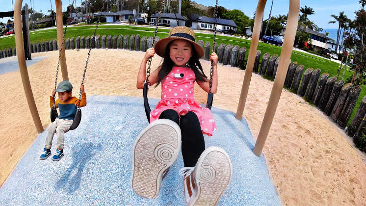 insta360 GO 3S montée sur la poitrine d'un enfant avec le pendentif magnétique pendant qu'ils jouent sur les balançoires